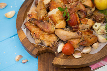 Whole roasted chicken garnished with tomatoes and apple on blue table.