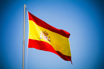 Fototapeta na wymiar Spain flag fluttering against blue sky on sunny day 