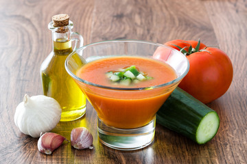 Traditional Spanish cold gazpacho soup and ingredients on wooden table

