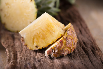 Pineapple slices and pineapple shelled Asian-style on the old wooden background. Tropical fruit concept