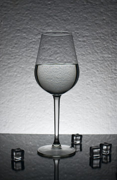 Glass of ice water on gray background    