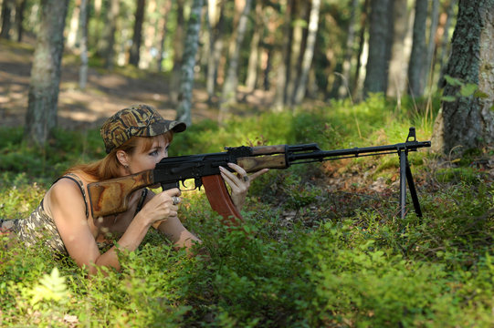 Beautiful girl in the woods with a machine gun Kalashnikov