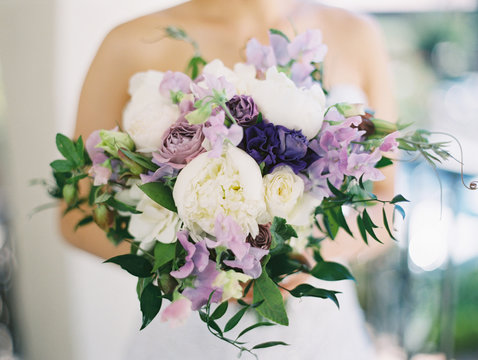Bride holding white and purple rose bouquet 