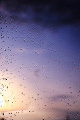 Rain / Water drop of rain on glass with sky outdoor background with  sunset / sun rise light effect (colorful light) on glass