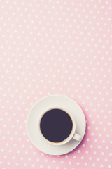 Coffee cup on pink dotted table