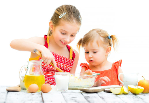 two cute little sisters cooking, on a white background
