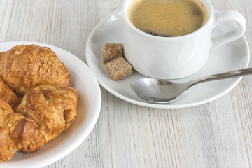 french breakfast/coffee cup and fresh croissants on a light wooden background with space for text