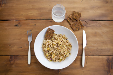 rice with vegetables dish in a wooden background with crackers and lemonade