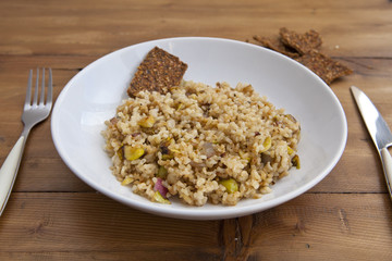 rice with vegetables dish in a wooden background with crackers and lemonade