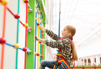 little girl climbing the wall on safety ropes in entertainment center