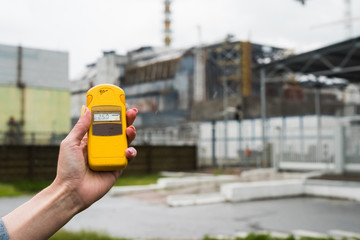 radiometer in hand with fourth Chernobyl reactor on the background