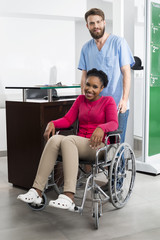 Smiling Patient Sitting In Wheelchair While Nurse Standing At Ho