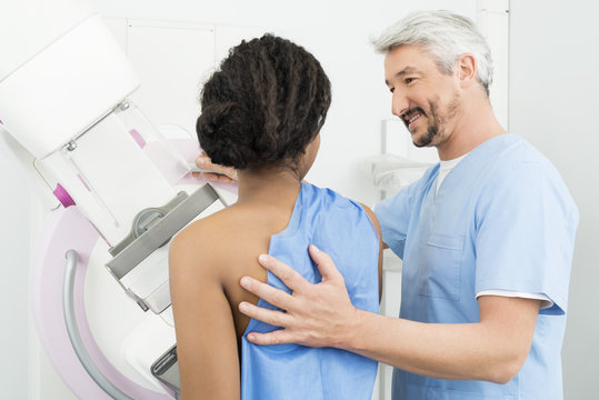 Mature Doctor Assisting Patient Undergoing Mammogram Test