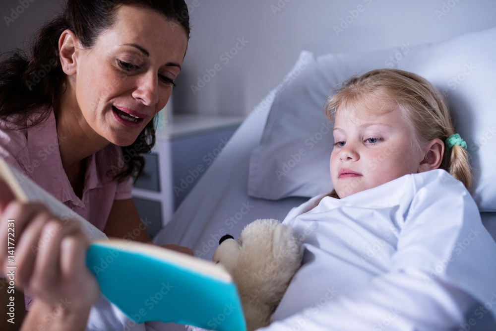 Poster girl on a hospital bed reading book with her mother