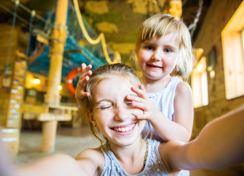 cute little girl with her hand on face of her funny friend doing selfie