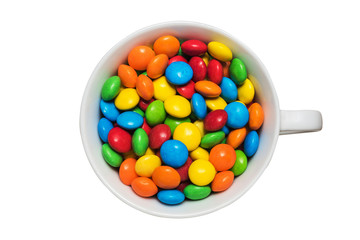 A cup with colorful tasty dragee on top isolated on white background