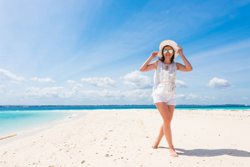 beautiful smiling girl in hat on a beach of blue ocean and sky on the background