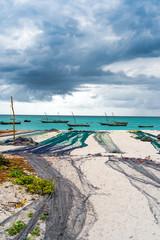 view of large fishing nets on african seashore with ocean and boats on the background