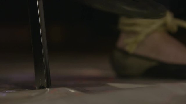 Close up of womans feet tied to a chair as she struggles to get free.