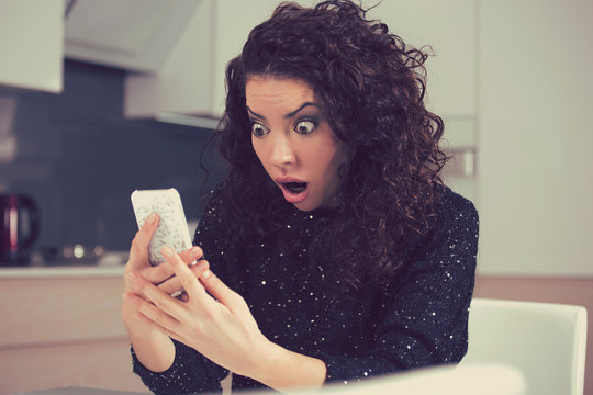 Funny shocked anxious woman looking at phone seeing bad photos message