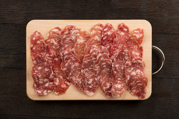 Italian salami sliced on wooden cutting board