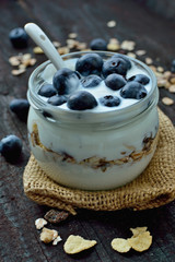 Fresh white yogurt with blueberries and oatmeals on brown wood table. Delicious natural breakfast. Culinary sweet dessert.