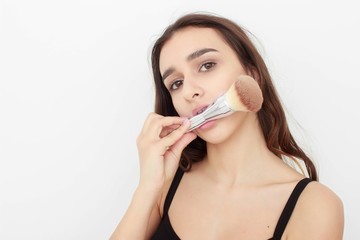 Portrait of beautiful woman applying a cosmetic isolated on beige