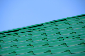 Obraz premium Green modern roof covered with tile effect PVC coated metal roof sheets against a blue sky