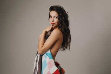Fashion photo of beautiful and young lady in swimsuits posing in studio, holding colorful towel