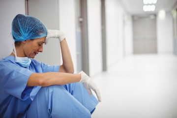 Sad surgeon sitting on floor in corridor - Powered by Adobe