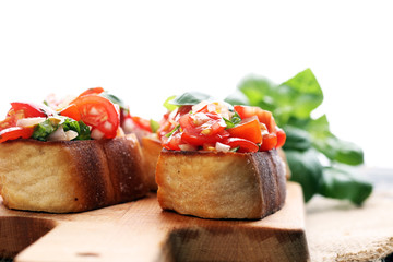 Tasty savory tomato Italian appetizers, or bruschetta, on slices of toasted baguette garnished with basil