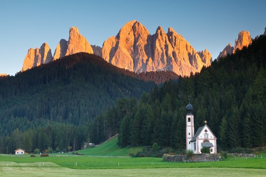 Funes valley, Dolomites, Trentino Alto Adige, Italy. The picturesque small church San Giovanni in Ranui at under of Odle at sunset.