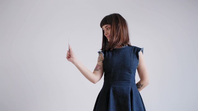 A wide shot of pretty brunette woman smirking into the camera in a cute manner and holding up a cutting knife prepared to open the surprise box.