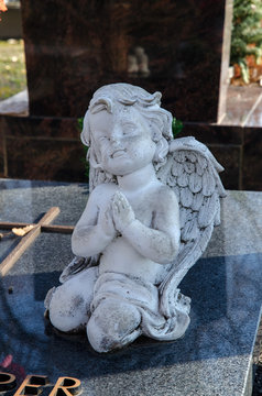 betende engelsfigur kniet an einem grabstein