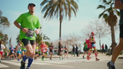 Sun shines on the palm seaside beach in Barcelona where unrecognizable runners participate in the healthy and sporty running event on the charitable occasion
