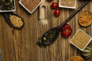 Bowls and spoons of various legumes on wooden table