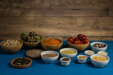 Bowls and spoons of various legumes on wooden table