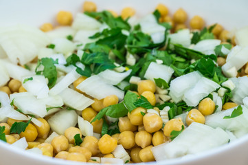Cheakpeas, onions and leaves of parsley. Close-up image of cooked chickpeas, chopped onion, garlic and fresh parsley in bowl