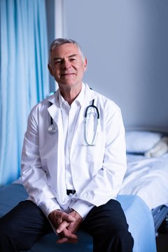 Portrait of male doctor sitting in ward