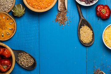 Bowls and spoons of various legumes on wooden table