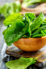Wooden bowl with spinach leaves.