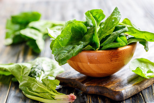 Wooden bowl with fresh spinach leaves.