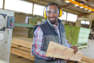 Man wearing earmuffs holding plank of wood