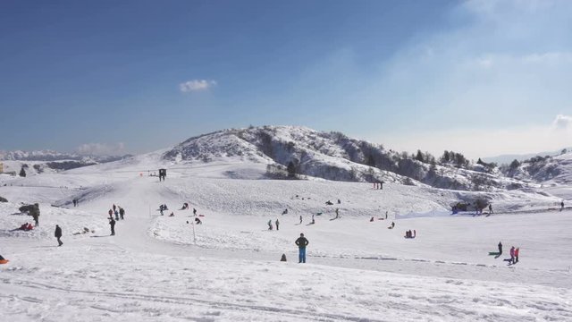 Crowd of Families on a Mountain Slope with Snow in a Sunny Winter Day