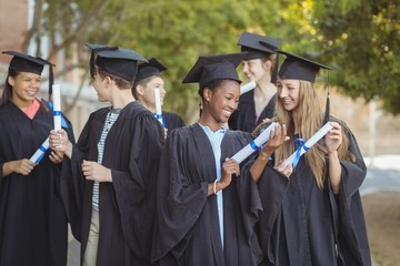 Graduate school kids standing with degree scroll 