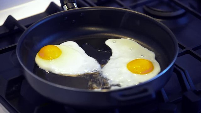 Fried eggs on a black frying pan closeup
,