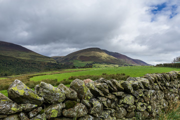 Dry Stone Wall among the green fields with mountain in the background in the Lake District