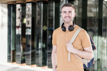 Man close up with headphones and back pack smiling