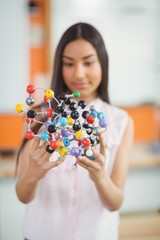 Schoolgirl experimenting molecule model in laboratory at school