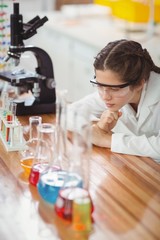 Thoughtful schoolgirl leaning on table in laboratory